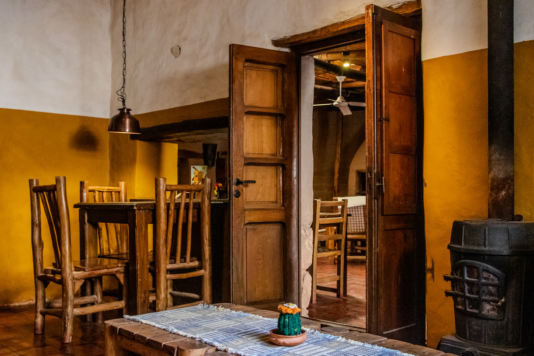 Comedor con paredes ocre, salamandra y mesas de madera